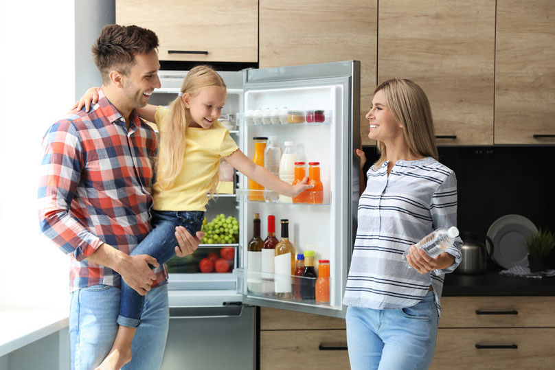 family in front of open refrigerator